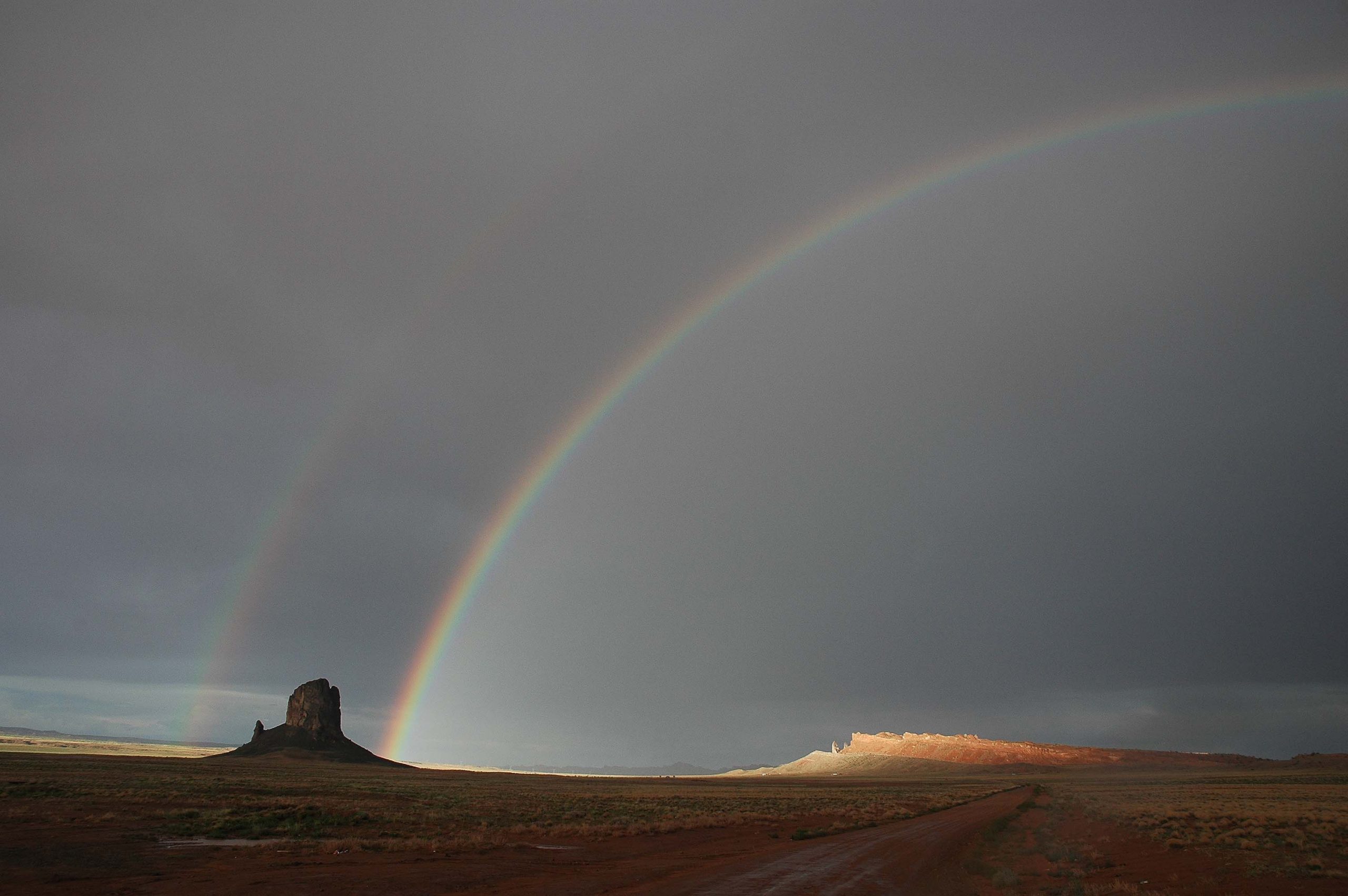 After the rain, the rainbow shines through. Photograph of rainbows in Utah.
